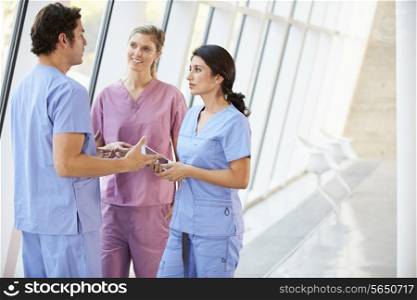Medical Staff Talking In Hospital Corridor With Digital Tablet