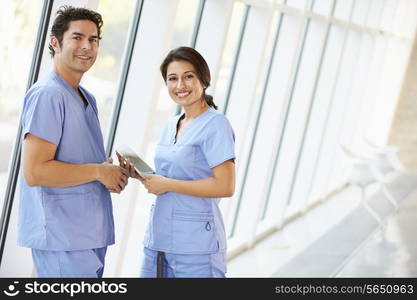 Medical Staff Talking In Hospital Corridor With Digital Tablet