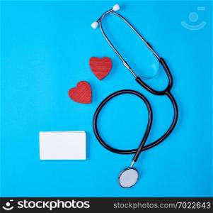 medical stethoscope and empty paper business cards on a blue background