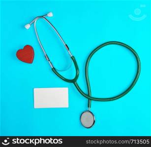 medical stethoscope and empty paper business cards on a blue background, top view
