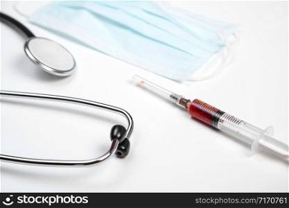 medical stethoscope, disposable mask and syringe with blood samples on a white isolated background