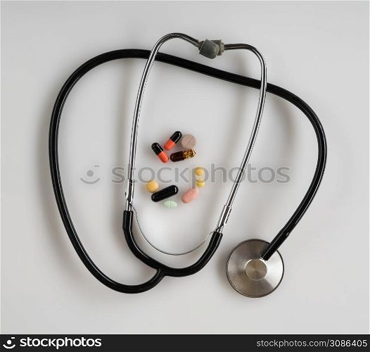 medical stethoscope with pills on white background, isolated. top view. stethoscope on white background