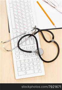 medical still life - phonendoscope on white keyboard and blank clipboard