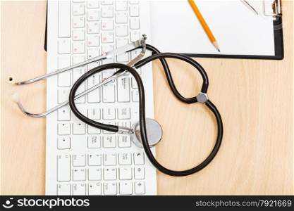 medical still life - stethoscope on white keyboard and blank clipboard