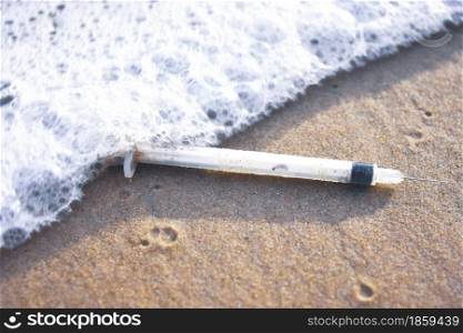 Medical syringe waste and foaming wave on the beach,Infectious wastes management concept