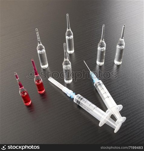 Medical syringes and ampules with vaccine on a wood board. Syringes and ampoules on a wood table.