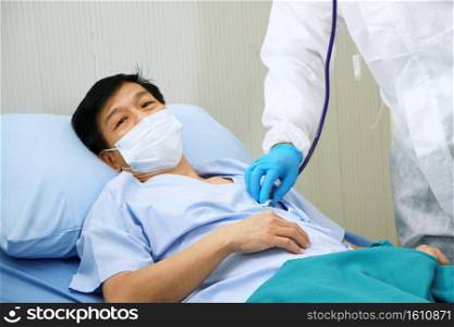Medical team in Personal Protective Equipment or PPE clothing and use a respirator for asian old man patient is Respiratory system infected with Covid 19 virus and research with tablet for treatment.