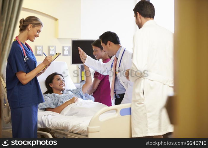 Medical Team Meeting Around Female Patient In Hospital Room