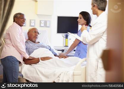 Medical Team Meeting With Senior Couple In Hospital Room