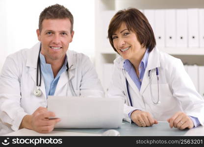 Medical team of male and female doctors sitting at desk.