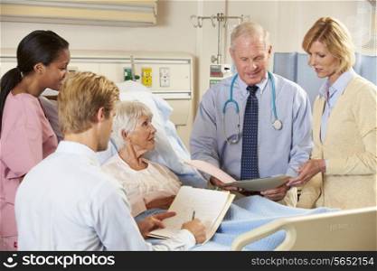 Medical Team Visiting Senior Female Patient In Bed