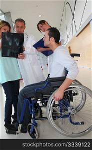Medical team with handicapped person looking at X-ray