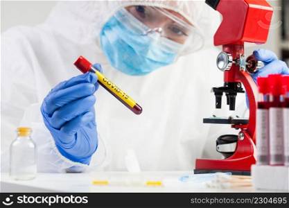 Medical technologist holding a COVID-19 test tube blood s&le, contagious dangerous Coronavirus disease global pandemic outbreak, hazard patient specimen laboratory testing analysis procedure