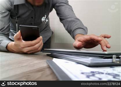 Medical technology concept. Doctor hand working with smart phone with medical chart document on wooden desk