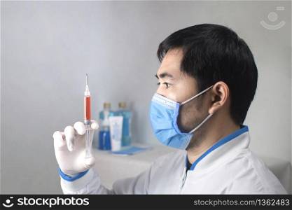 Medical vaccine syringe for medicine injection treatment holding in a hand of the doctor,Doctor wearing medical mask for prevent germs,Coronavirus,Covid-19.