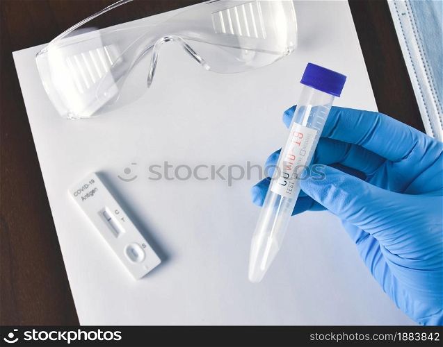 Medical worker holding Covid-19 extraction tube and cotton swab in the tube on desk and laboratory accessories background,Coronavirus infectious protect concept