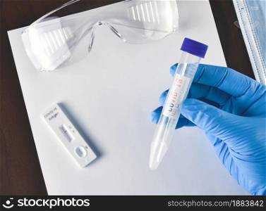 Medical worker holding Covid-19 extraction tube and cotton swab in the tube on desk and laboratory accessories background,Coronavirus infectious protect concept
