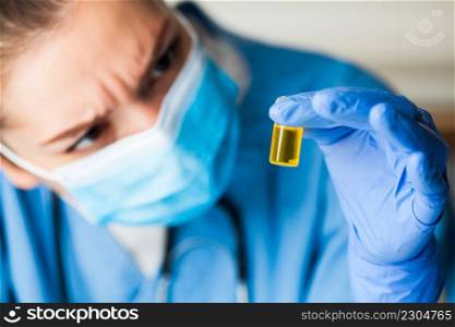 Medical worker inspecting&oule vial bottle filled with yellow liquid,COVID-19 potential vaccine cure develop,convalescent patient platelet rich blood plasma transfusion,Coronavirus therapy concept