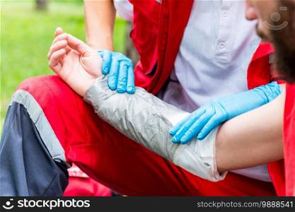 Medical worker treating burns on male’s hand. First aid treatment outdoors. First aid practice
