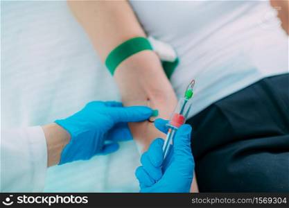 Medical worker with PPE taking blood sample from patient in a hospital