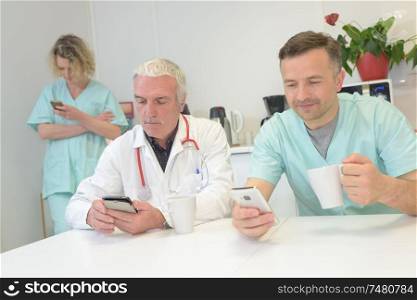 Medical workers on a break, looking at their cellphones
