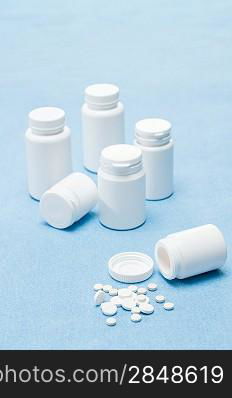 Medicament pills tablets spilled from bottle on medical blue background