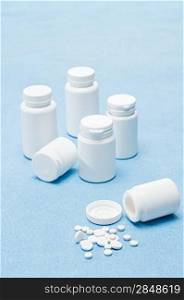 Medicament pills tablets spilled from bottle on medical blue background