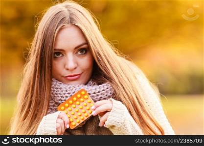 Medication, health concept. Woman with vitamins for autumn. Attractive lady with long hair wearing warm autumnal clothing.. Woman with vitamins for autumn.