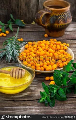 Medicinal the decoction of buckthorn berries. Ripe berries of sea buckthorn in saucer on wooden background