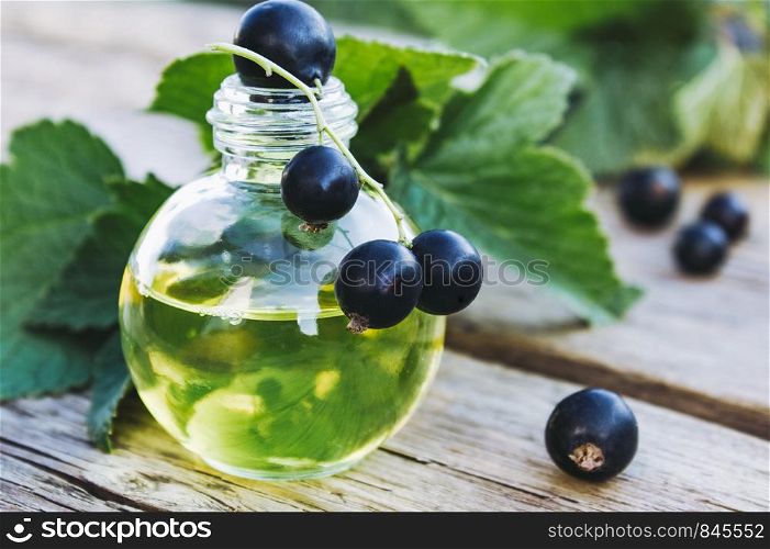 Medicinal tincture with black currant in a glass bottle. Cold remedy extract of black currant. Close-up.. Medicinal tincture with black currant in a glass bottle. Cold remedy extract of black currant.
