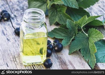 Medicinal tincture with black currant in a glass bottle. Cold remedy extract of black currant. Close-up.. Medicinal tincture with black currant in a glass bottle. Cold remedy extract of black currant.
