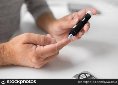 medicine, age, diabetes, health care and old people concept - senior man with glucometer checking blood sugar level at home. senior man with glucometer checking blood sugar