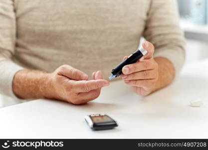 medicine, age, diabetes, healthcare and old people concept - close up of senior man with glucometer making blood test and checking sugar level at home. close up of old man with glucometer blood test