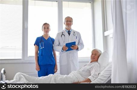 medicine, age, health care and people concept - doctor and nurse with tablet pc computer visiting senior patient woman at hospital ward