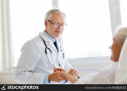 medicine, age, health care and people concept - doctor checking senior woman pulse at hospital ward