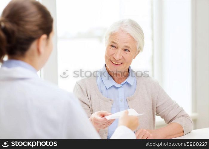 medicine, age, health care and people concept - doctor giving prescription to happy senior woman at hospital