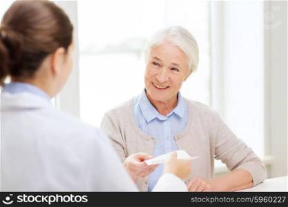 medicine, age, health care and people concept - doctor giving prescription to happy senior woman at hospital