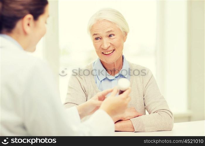 medicine, age, health care and people concept - doctor showing pills to happy senior woman at hospital