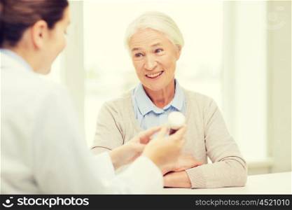 medicine, age, health care and people concept - doctor showing pills to happy senior woman at hospital