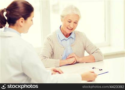medicine, age, health care and people concept - doctor with clipboard and senior woman meeting at hospital