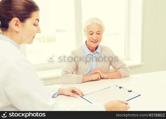 medicine, age, health care and people concept - doctor with clipboard and senior woman meeting at hospital