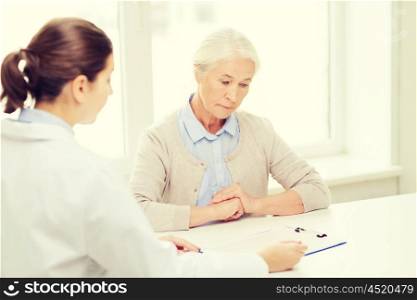 medicine, age, health care and people concept - doctor with clipboard and senior woman meeting at hospital