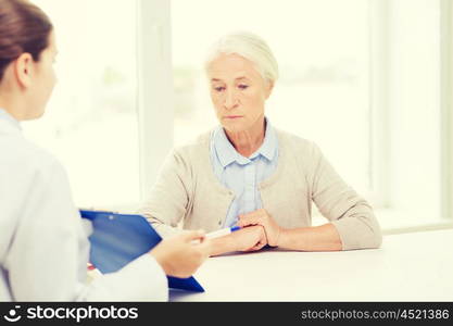 medicine, age, health care and people concept - doctor with clipboard and senior woman meeting at hospital