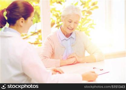 medicine, age, health care and people concept - doctor with clipboard and senior woman meeting at hospital. doctor with clipboard and senior woman at hospital