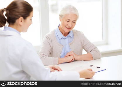 medicine, age, health care and people concept - doctor with clipboard and senior woman meeting at hospital