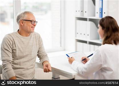 medicine, age, health care and people concept - happy senior man and doctor with clipboard meeting and talking in medical office at hospital