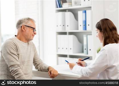 medicine, age, health care and people concept - senior man and doctor writing on clipboard in medical office at hospital