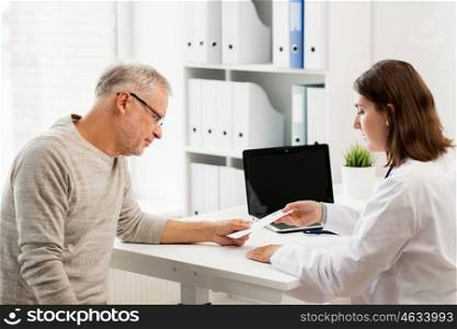 medicine, age, health care and people concept - senior man and doctor with prescription meeting in medical office at hospital