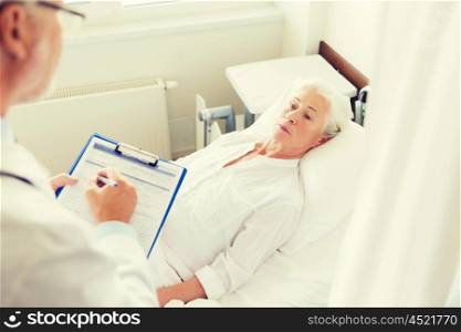 medicine, age, health care and people concept - senior woman and doctor writing to clipboard at hospital ward