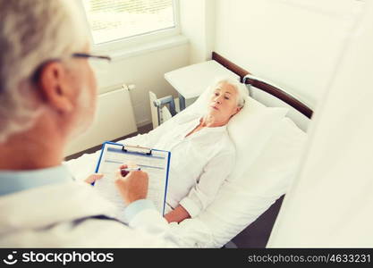 medicine, age, health care and people concept - senior woman and doctor writing to clipboard at hospital ward